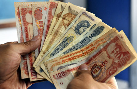 A man counts Bolivian Pesos in La Paz on December 15, 2011. AFP PHOTO/ Aizar Raldes